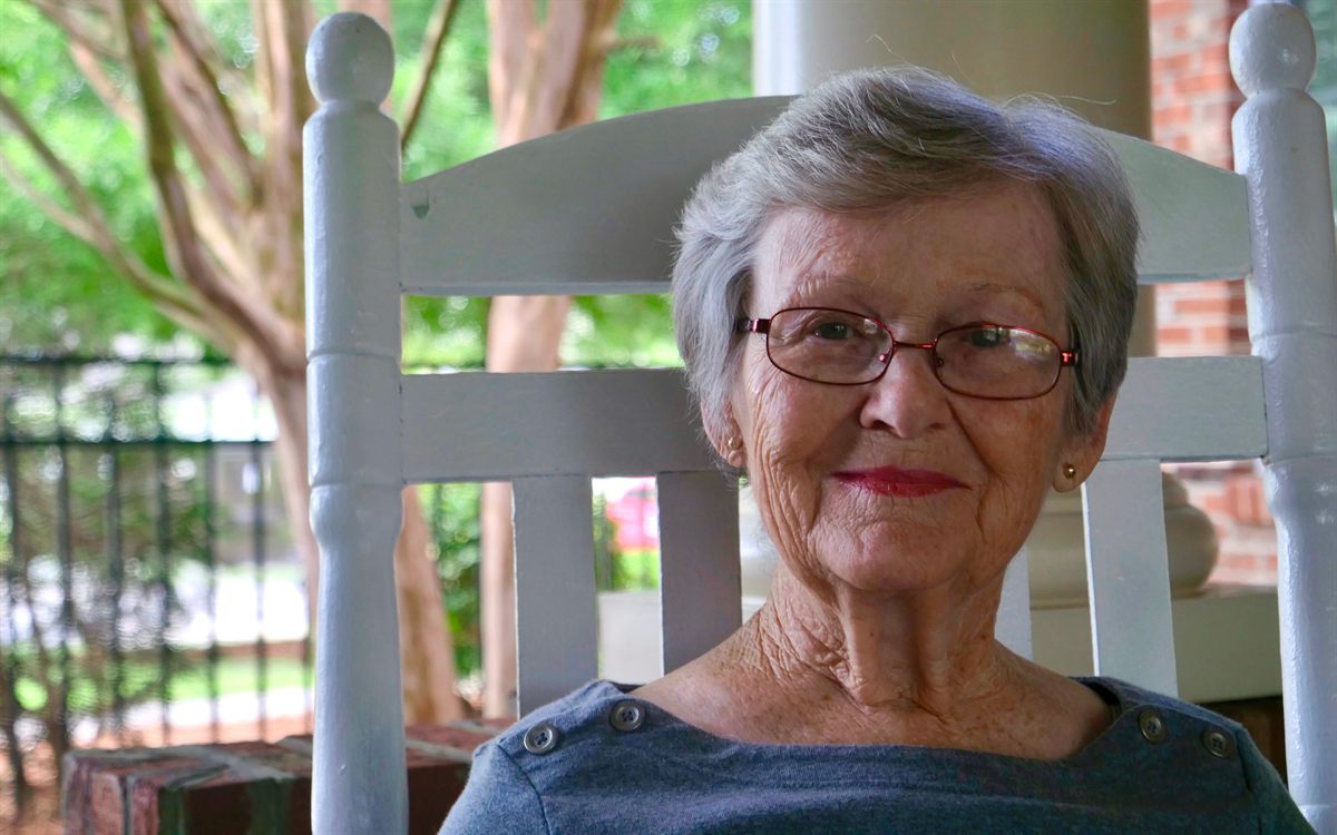 A resident smiling from her rocking chair